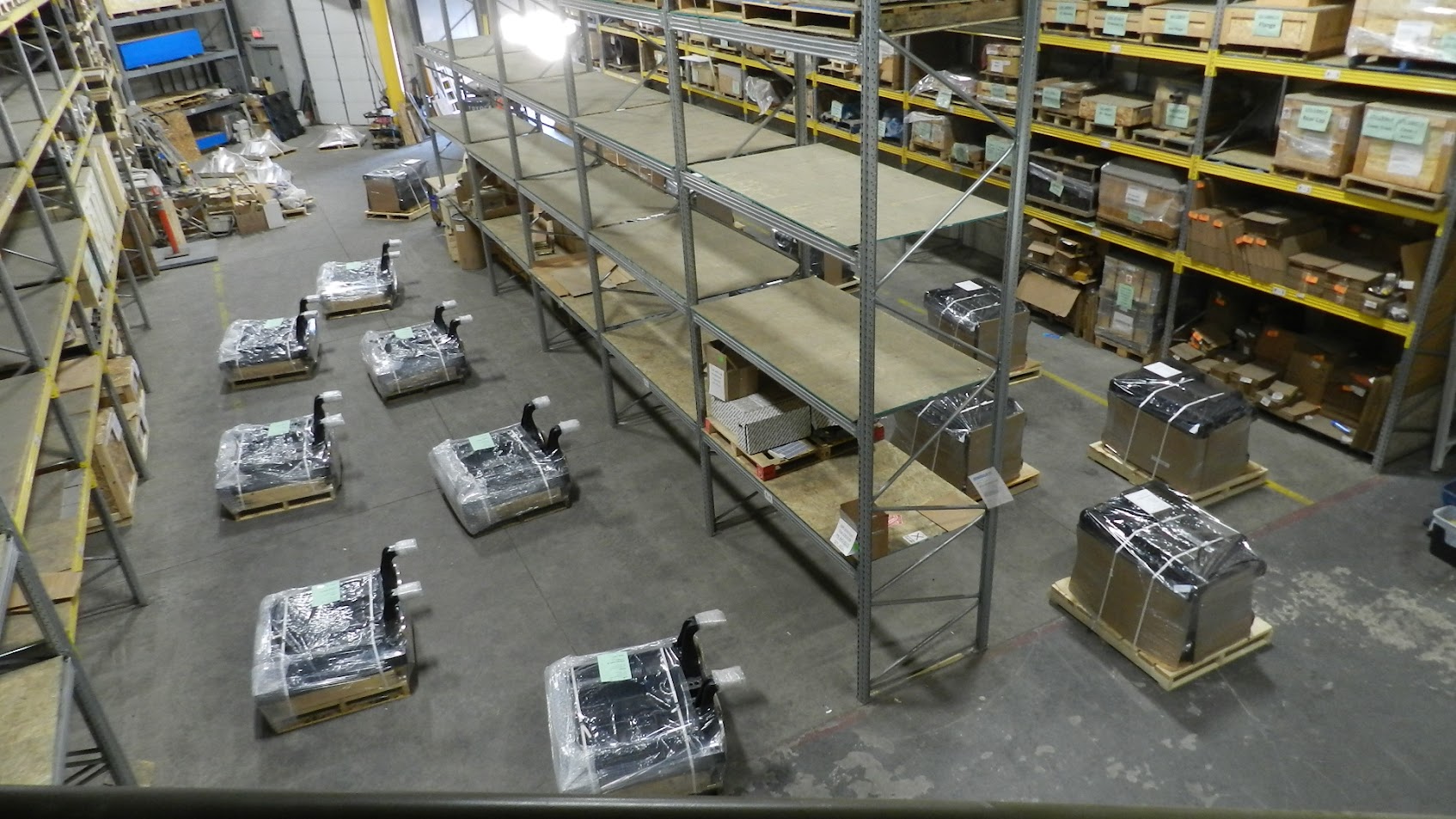Warehouse floor with locomotive components on pallets and multi-level shelving